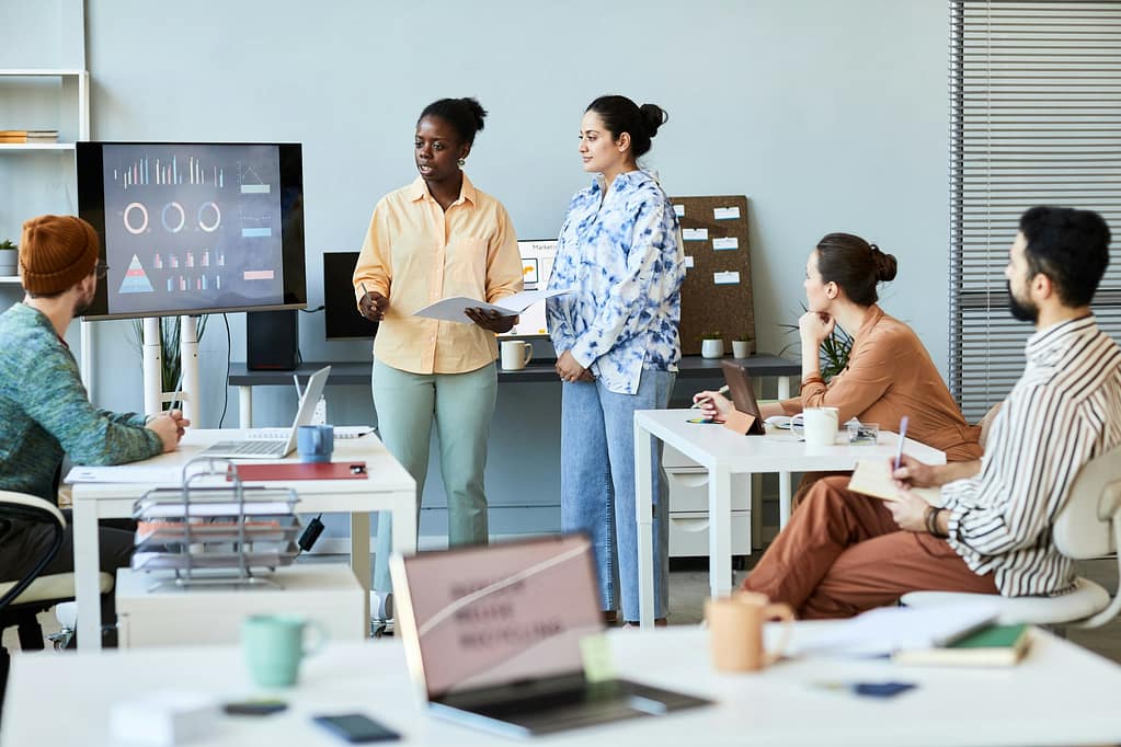 Young confident teacher or coach standing in front of audience at seminar